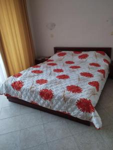 Una cama con un edredón blanco con flores rojas. en Renta BG Apartments in Tsarevo, en Tsarevo