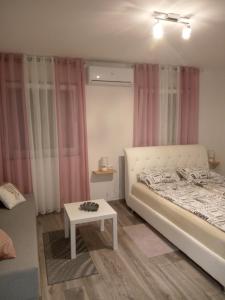 1 dormitorio con cama blanca y cortinas rosas en Guest House Happy day, en Slunj
