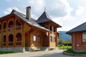 una grande casa in legno con tetto nero di Гостинний двір КАРПАТІЯ, Верховина a Verkhovyna