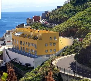 a yellow building on a hill next to the ocean at Las Teresitas Apartment in San Andrés