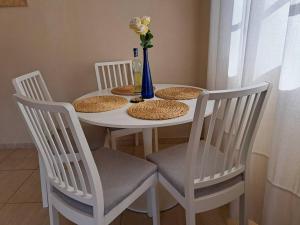 a white table with three chairs and a vase with flowers at Las Teresitas Apartment in San Andrés