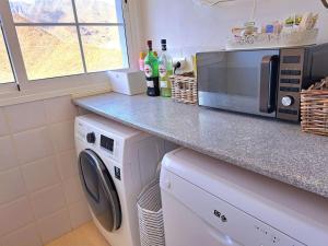 a kitchen with a washing machine and a microwave at Las Teresitas Apartment in San Andrés