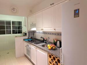a kitchen with white cabinets and a sink with fruit on the counter at Las Teresitas Apartment in San Andrés
