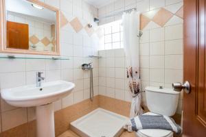een badkamer met een wastafel, een toilet en een spiegel bij Studios Maria in Potos