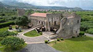 un antico edificio in pietra con un campo verde e montagne sullo sfondo di B&B Il Grillo a Santa Maria del Cedro