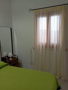 a bedroom with a green bed and a window at Favignana Vacanze in Favignana