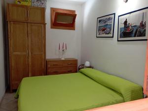 a bedroom with a green bed and a wooden cabinet at Favignana Vacanze in Favignana