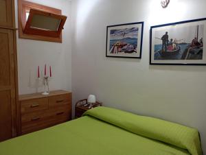 a bedroom with a green bed and pictures on the wall at Favignana Vacanze in Favignana