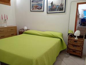 a bedroom with a green bed and pictures on the wall at Favignana Vacanze in Favignana