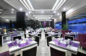 un restaurante con mesas y sillas de color púrpura y blanco en Quest Hotel Balikpapan by ASTON, en Balikpapan