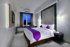 Quest Hotel Balikpapan by ASTON في باليكبابان: غرفة نوم بسرير كبير ونافذة