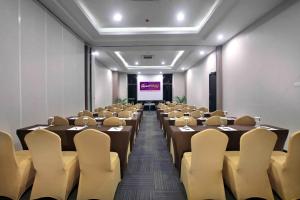 una sala de conferencias con mesas, sillas y una pantalla en Quest Hotel Balikpapan by ASTON en Balikpapan