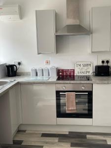 a kitchen with white cabinets and an oven at Middlecroft in Chesterfield