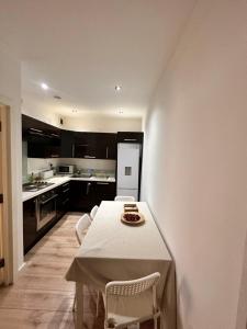 Modern 2 bedroom flat next to Liverpool Street في لندن: مطبخ مع طاولة وبعض الكراسي وطاولة ومطبخ