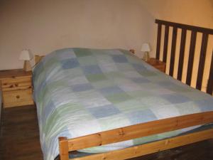 een bed met een blauwe en groene plaid deken erop bij Gîte Mas des cabanes en petite camargue in Aimargues