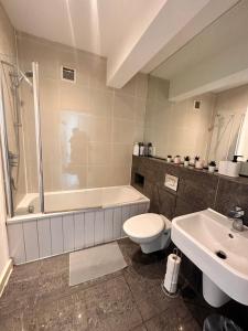 a bathroom with a tub and a toilet and a sink at Modern 2 bedroom flat next to Liverpool Street in London