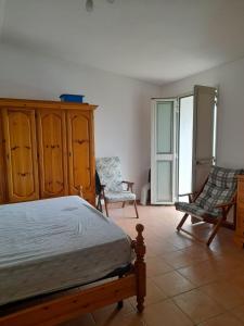a bedroom with a bed and two chairs at Casa Vacanza Giacu in Arzana