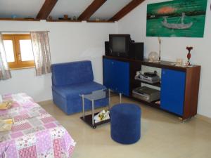 a living room with a blue chair and a tv at Studio Apartment Nera in Rovinj