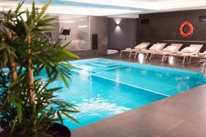 a swimming pool in a room with chairs and a pool at MASA Hotel & Spa Campo Grande Collection in Lisbon