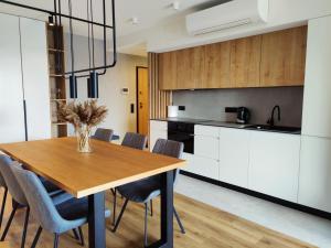 a kitchen and dining room with a wooden table and chairs at Water Harmony Darłówko in Darłowo