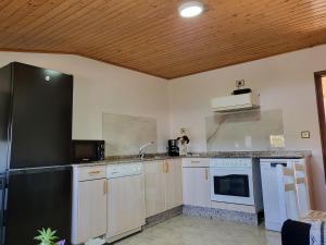uma cozinha com armários brancos e um frigorífico preto em Casa Bascuas no Portonovo