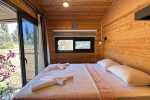 Cama grande en habitación de madera con ventana en Tiny House Patara, en Kas