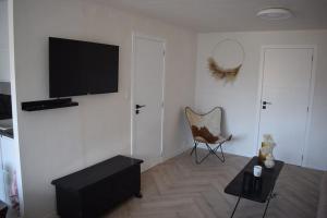 Una sala de estar con un televisor de pantalla plana y una silla. en Appart De Pauw Nieuport, en Nieuwpoort