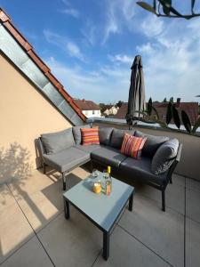 a patio with a couch and a table and an umbrella at Rückzugsort im Rebenmeer mit Grill & Parkplatz in Venningen