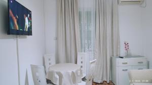 a white dining room with a white table and chairs at Pejovic Guest House in Sutomore