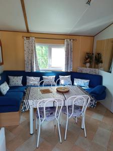 a living room with a table and a blue couch at Mobil home 6 personnes climatisation Sainte Croix du Verdon - Gorges du Verdon in Sainte-Croix-de-Verdon