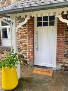 a white door with a welcome sign in front of a brick house at Le Sartisfait in Jalhay