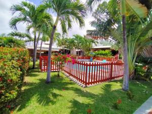 een rood hek in een tuin met palmbomen en bloemen bij ISK LOCATION in Sainte-Rose