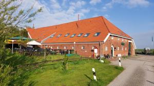 un gran edificio de ladrillo rojo con techo naranja en Hofcafé & Ferienhof Akkens en Greetsiel