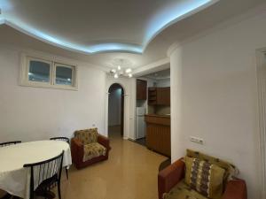 a living room with a table and chairs and a kitchen at Apartment near the sea in Batumi