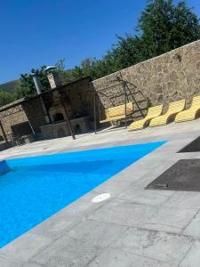 a swimming pool with blue water and yellow chairs at Luysi Garden in Garni