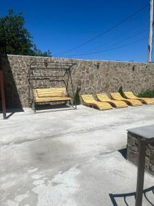 eine Reihe gelber Stühle neben einer Steinmauer in der Unterkunft Luysi Garden in Garni