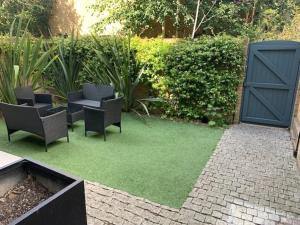 une cour avec 2 chaises et de l'herbe verte dans l'établissement Central London Luxury 4 Bed Home, à Londres