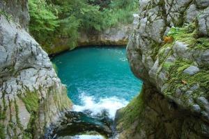 ein großer Pool mit blauem Wasser in einem felsigen Canyon in der Unterkunft Kulla e Sadri Lukes in Theth