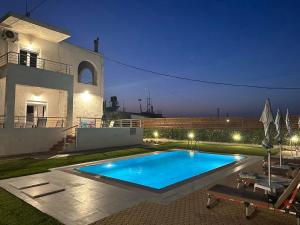 a swimming pool in front of a house at night at Amazing Villa Chrysanthi with private pool in Heraklion in Epáno Váthia