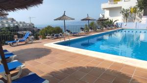 ein Pool mit Stühlen und Sonnenschirmen neben einem Gebäude in der Unterkunft Una casa con vistas in Faro de Cullera + 18 Fotos