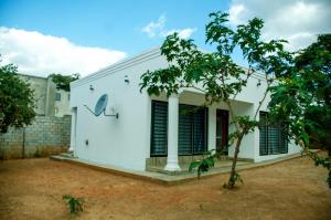 a white house with black shutters at Nsunge Nsunge Farm and Natural Resort in Lusaka