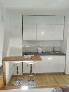 uma cozinha com armários brancos e um balcão com bancos em Hedonic Studio em Belgrado