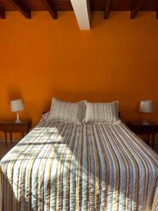 1 cama en un dormitorio con pared de color naranja en Departamento en Vistalba, Lujan con vista a la Montaña en Luján de Cuyo