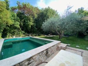 a swimming pool in a yard with a stone wall at Chambre Foret du Mas des Fontaines in Montagnac