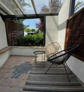 - une terrasse avec 2 chaises et une table dans l'établissement Moderne Ferienwohnung mit Terrasse, à Guxhagen