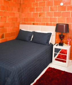 a bedroom with a bed and a brick wall at Barra da Tijuca Rio de Janeiro ilha da gigoia in Rio de Janeiro