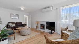 a living room with a television and a fireplace at The Links - Mount Maunganui Holiday Home in Mount Maunganui