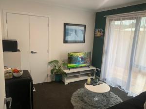 uma sala de estar com uma televisão de ecrã plano e um sofá em Hall Street Haven em Te Awamutu
