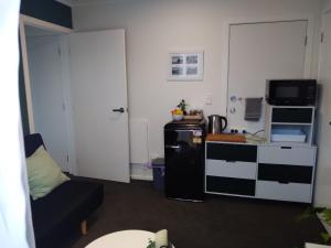 a small living room with a couch and a refrigerator at Hall Street Haven in Te Awamutu