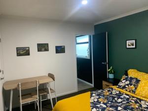 a bedroom with a bed and a desk next to a door at Hall Street Haven in Te Awamutu